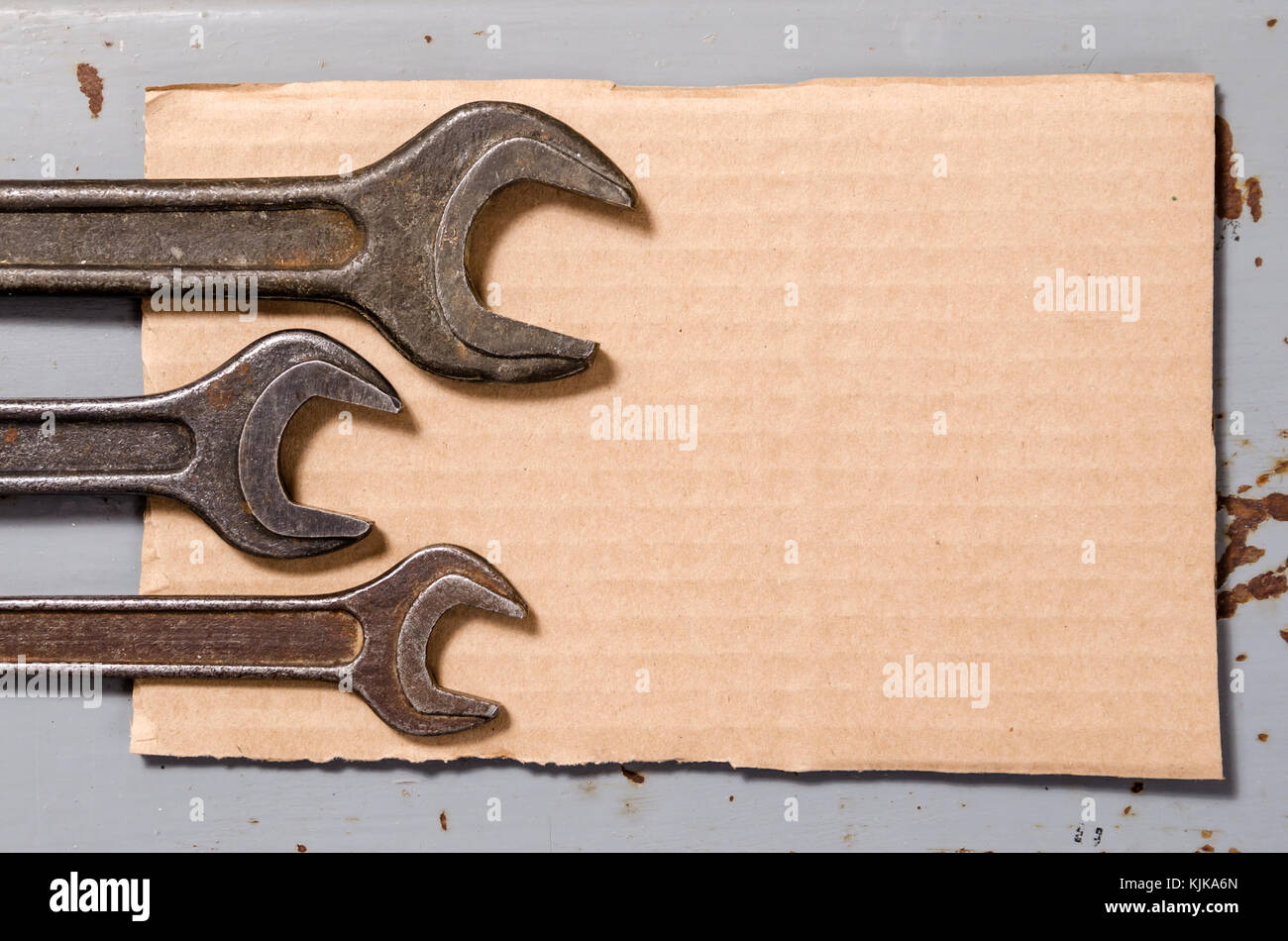 several wrenches and piece of corrugated paper box on the background of metal painted plates Stock Photo