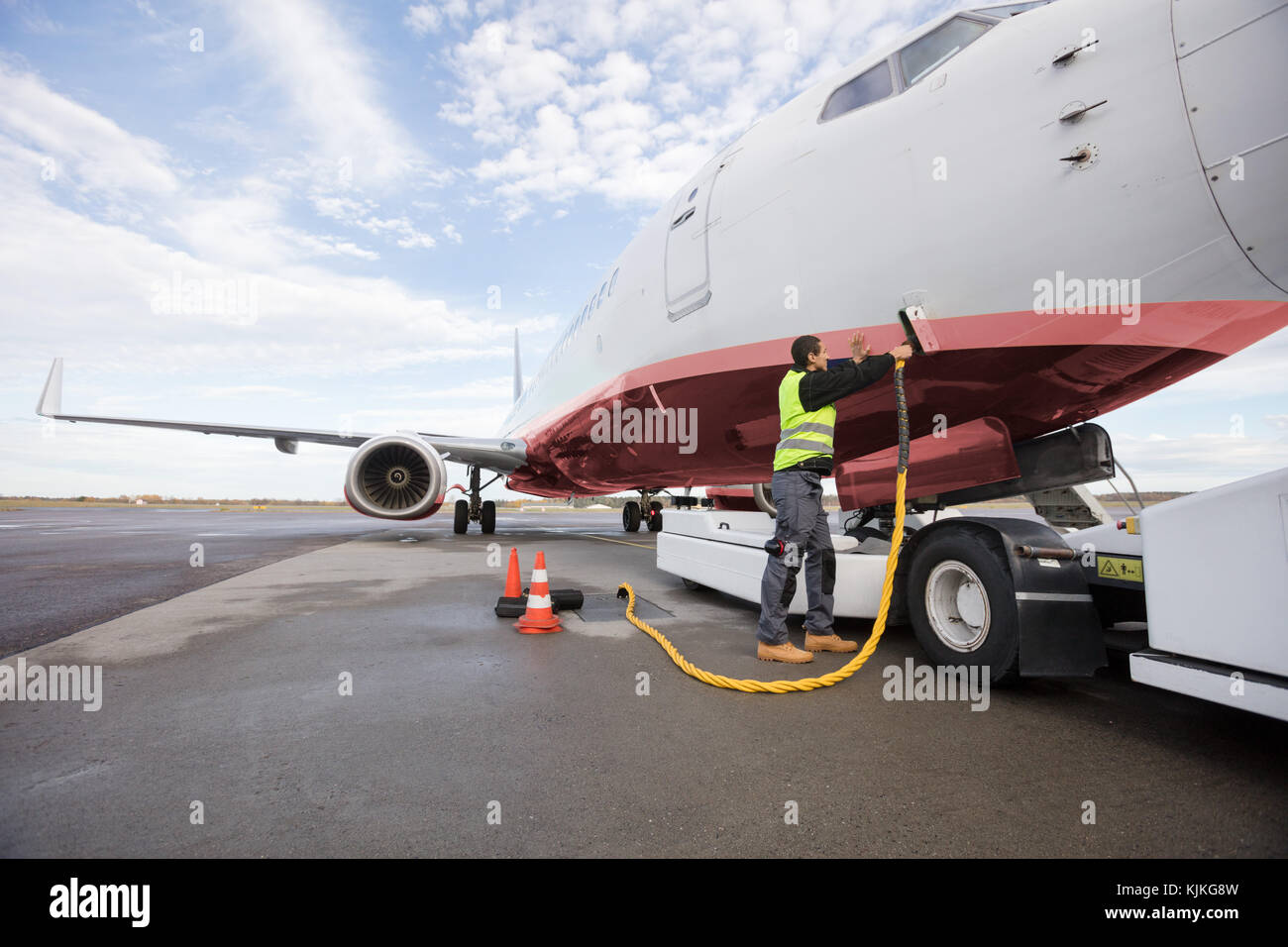 Full length of crew member charging airplane on runway Stock Photo