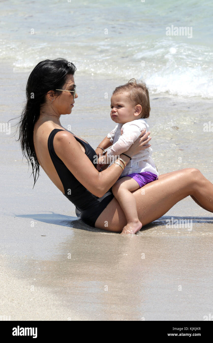 MIAMI BEACH, FL - MAY 03: Kourtney Kardashian wearing shorts and a black  one piece swimsuit enjoys a beach day with her kids Mason, Penelope and  Reign Disick on May 3, 2016