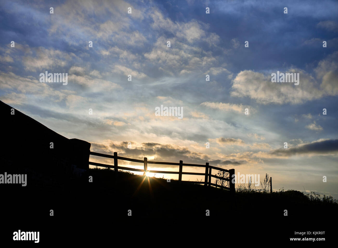 Setting sun behind a farm fence and a bridge Stock Photo