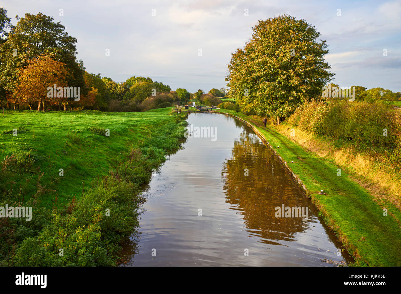 Woman walking along the Shropshire Union canal on an autumn evening at Audlem lock number two Stock Photo