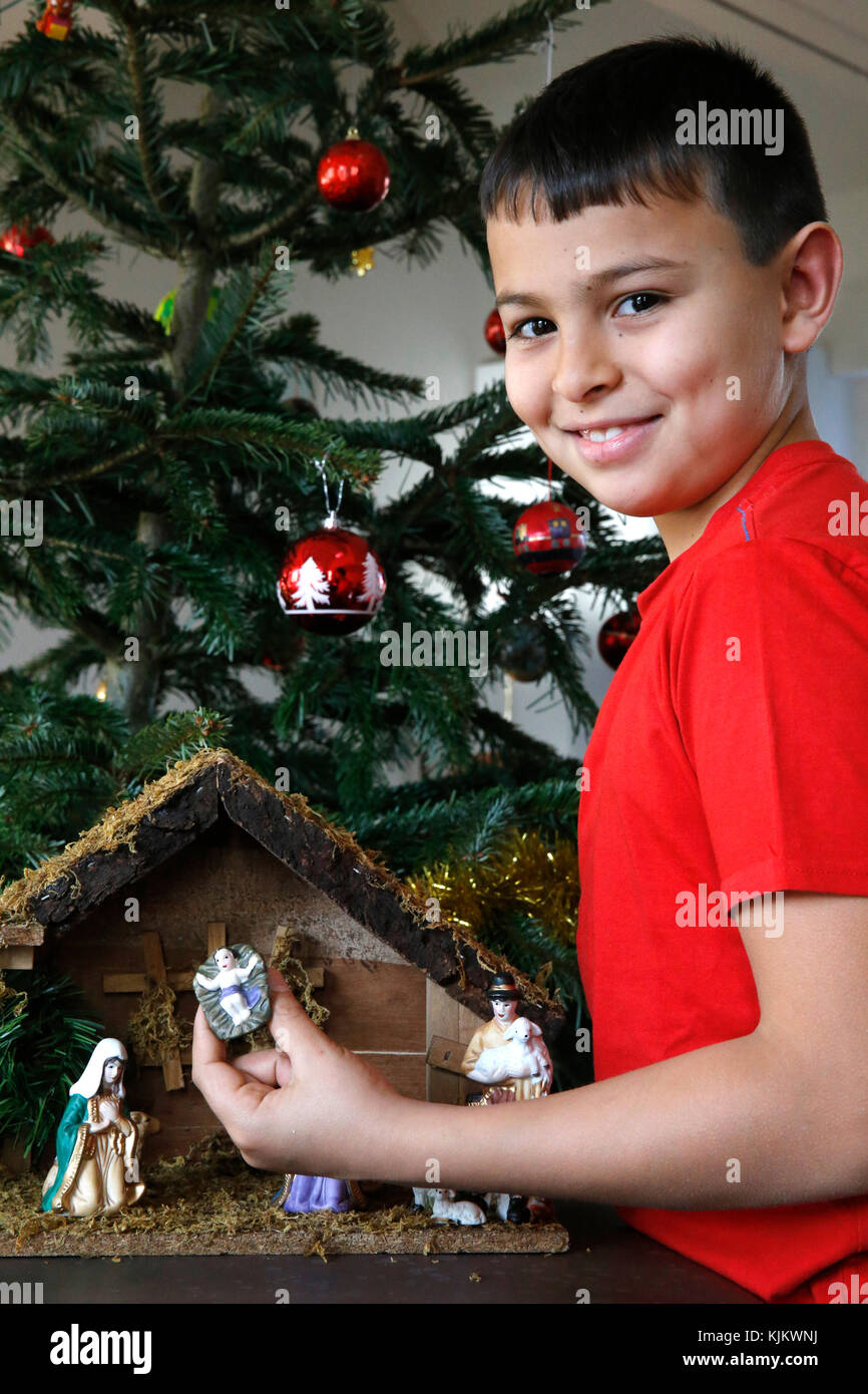 10-year-old boy laying a Christmas nativity scene. France. Stock Photo