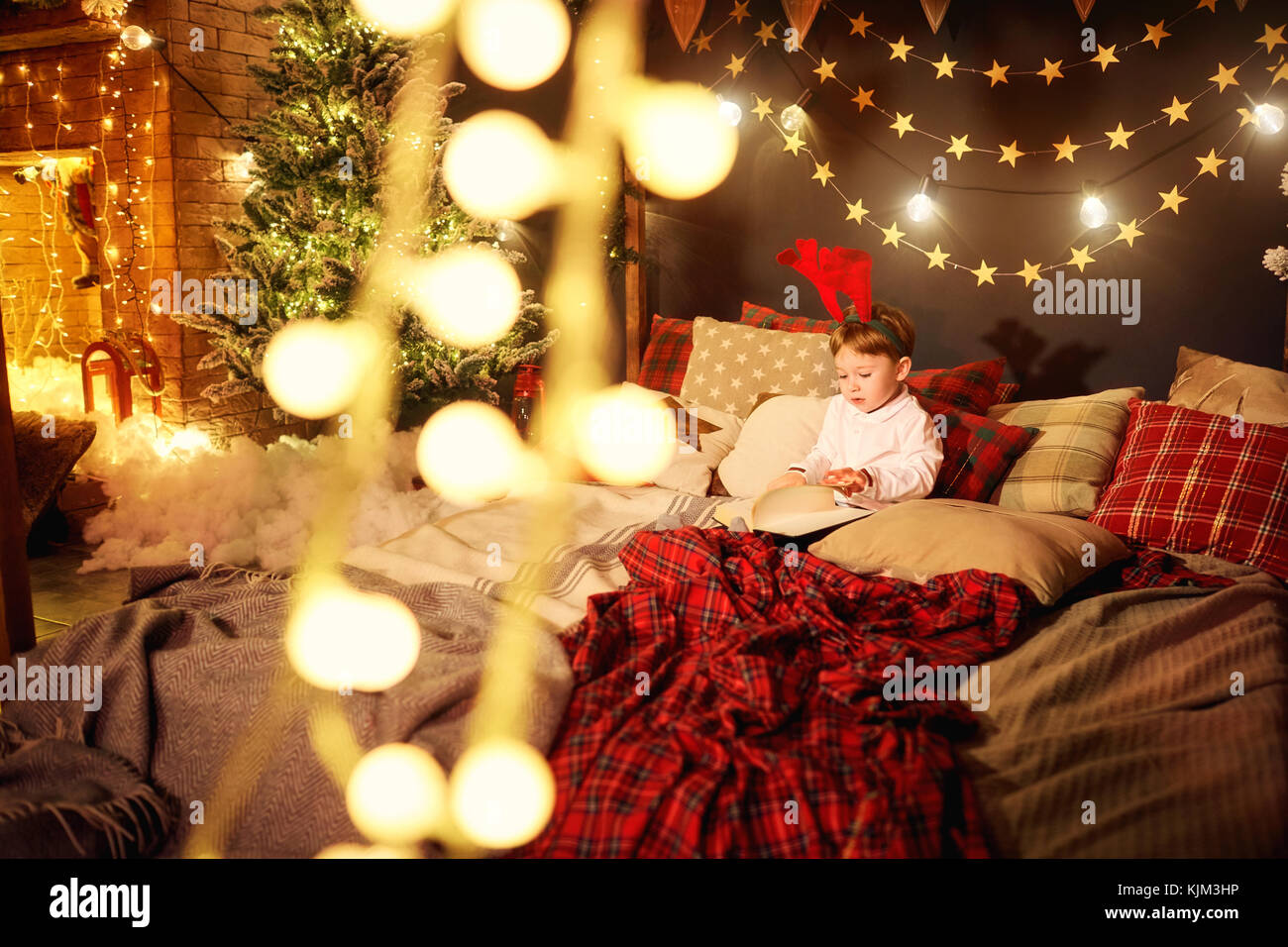 A child little boy is reading a book in the Christmas room Stock Photo