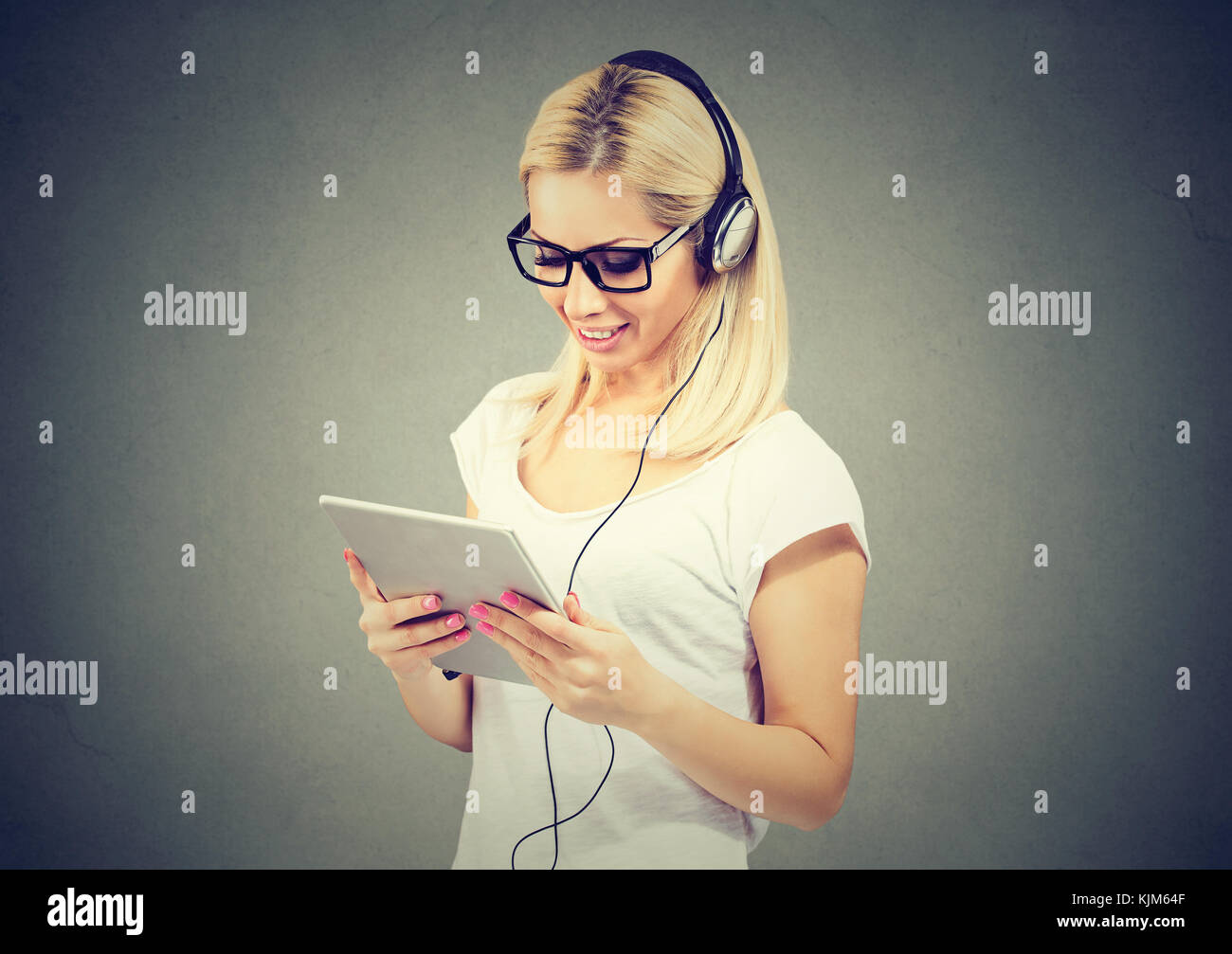 Happy woman using tablet computer listening to music with headphones Stock Photo
