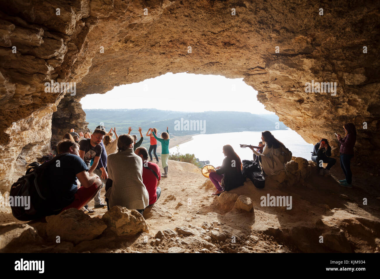 Group of people singing, dancing and relaxing at the famous touristic cave, GHAR IL-MIXTA at RAMLA BAY. Stock Photo