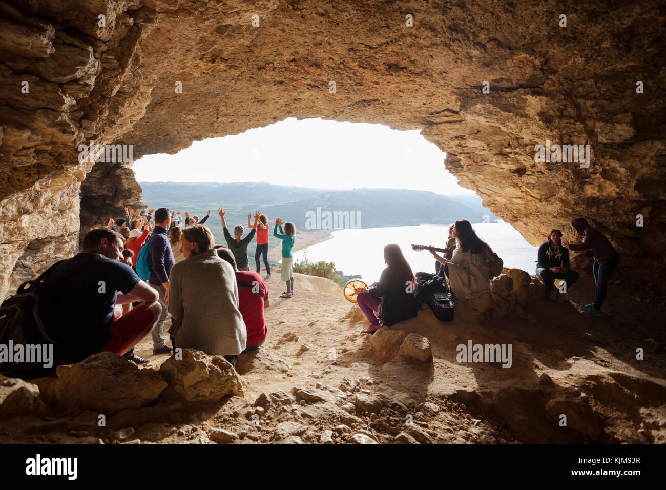 Group of people singing, dancing and relaxing at the famous touristic cave, GHAR IL-MIXTA at RAMLA BAY. Stock Photo