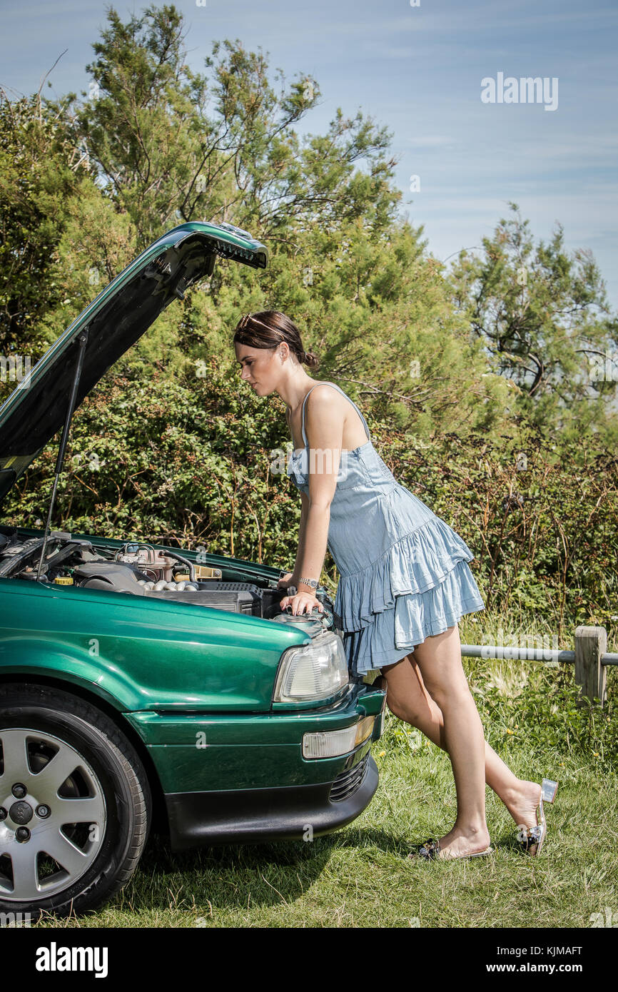 A beautiful young woman looking disappointed because her car has broken down. Stock Photo