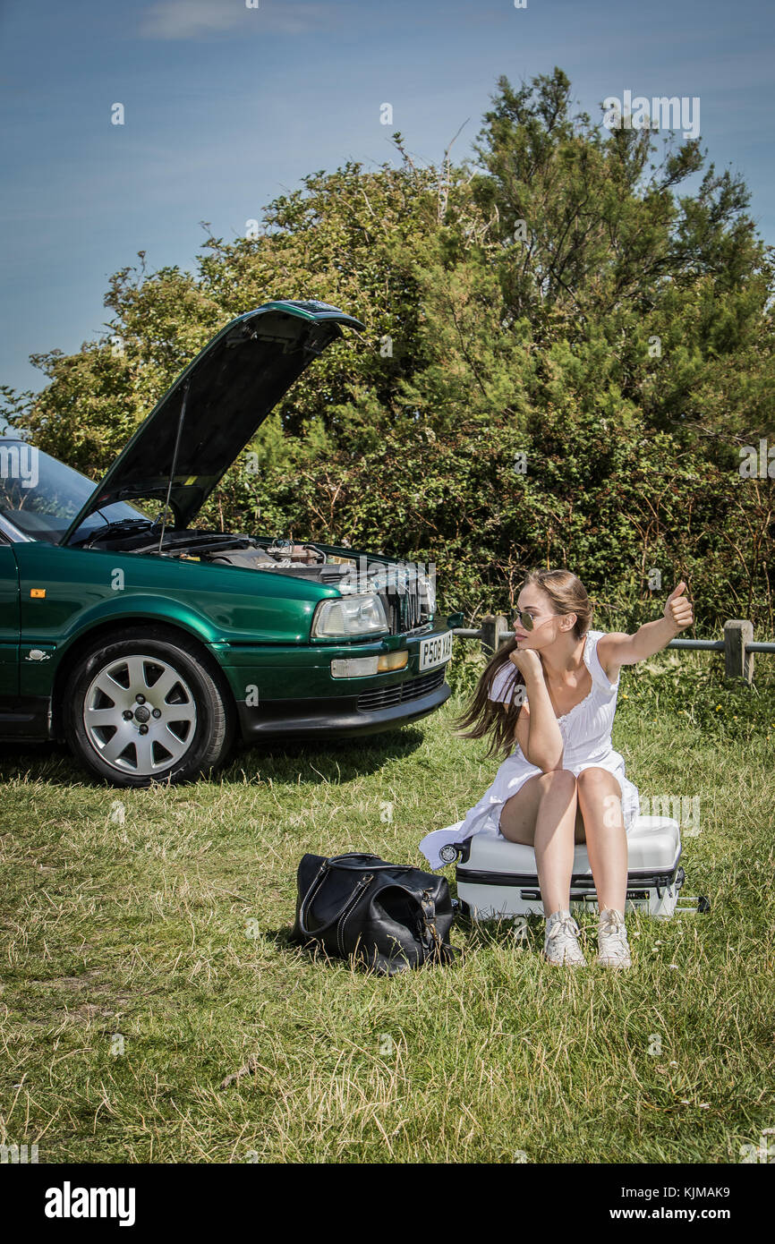 A beautiful young woman looking disappointed because her car has broken down. Stock Photo