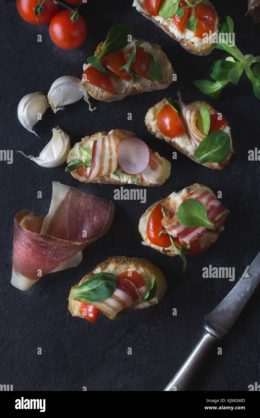 Bruschettas on the table with bacon and grilled tomato from above,selective focus Stock Photo