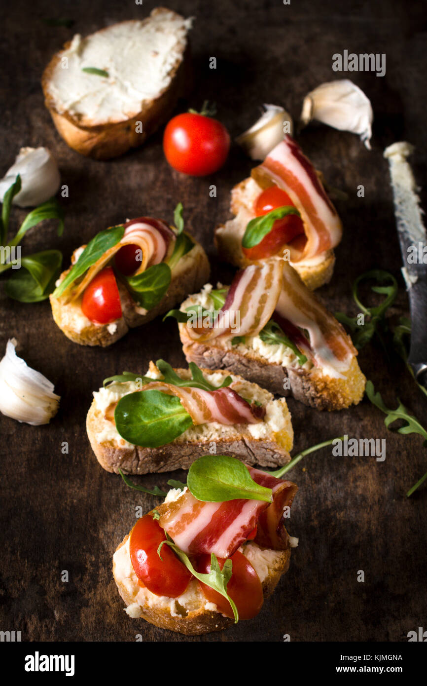 Bruschettas with bacon and tomato on wooden background,selective focus Stock Photo