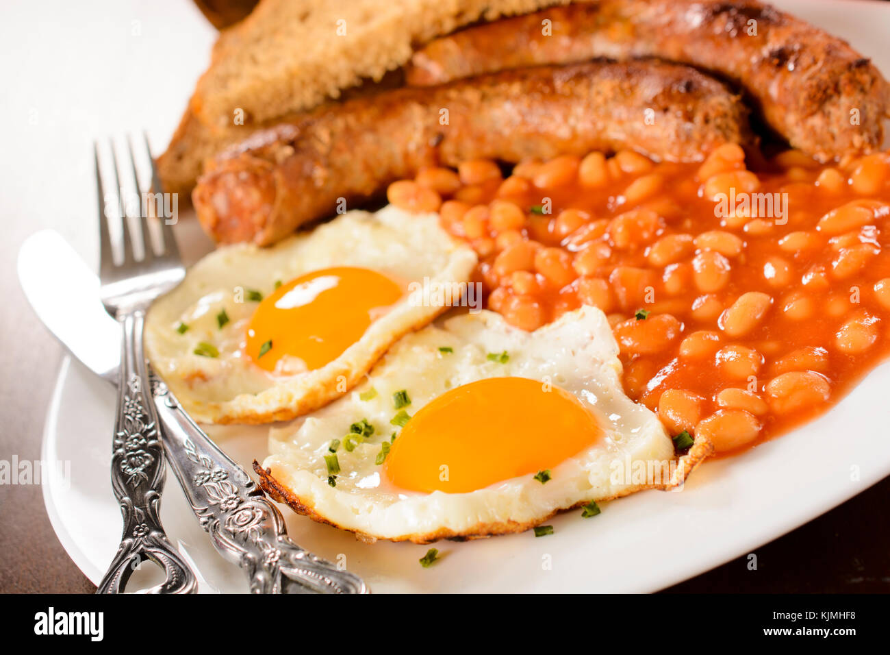 Eggs,beans and sausage in the plate.Selective focus on the front egg Stock Photo