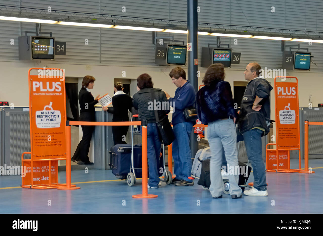 leisure passengers at the Terminal3 easyJet check-in desks with 'no carry-on baggage weight restrictions' signs in French language Stock Photo