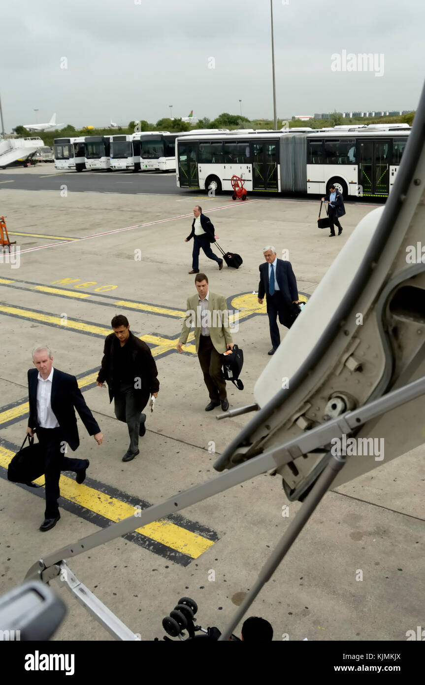 passengers with carry-on baggage walking across the apron from the bus to board the 737 Stock Photo