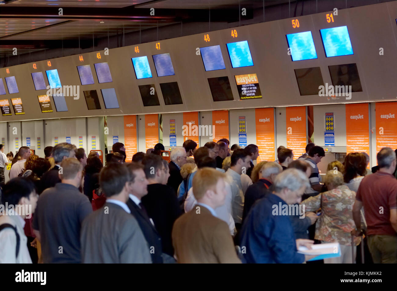 busy easyJet check-in with businessmen and leisure passengers in a crowded queue Stock Photo