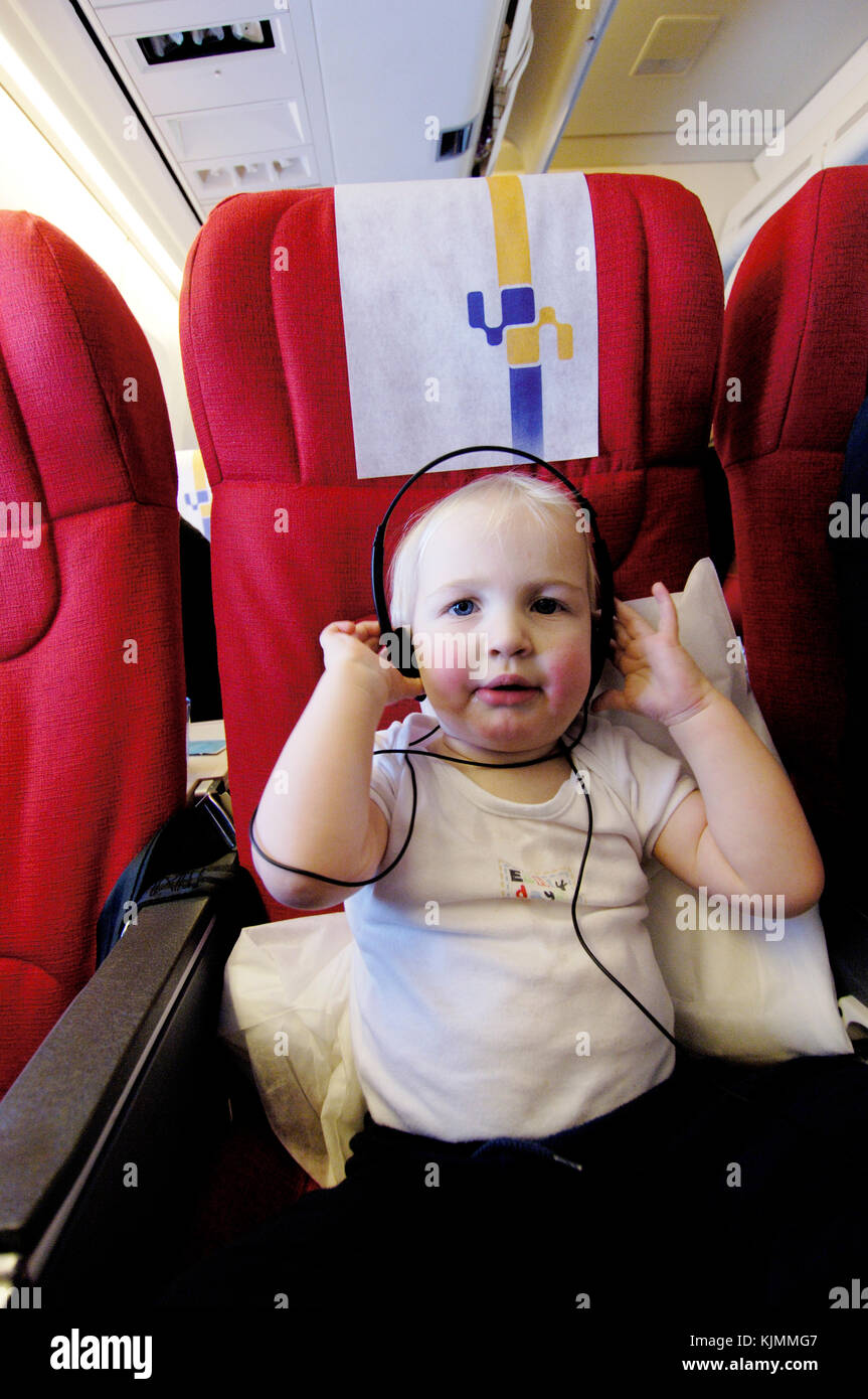 1.5 year old baby boy Henry wearing headphones on a long haul flight in the economy-class cabin LGW-ANU Stock Photo