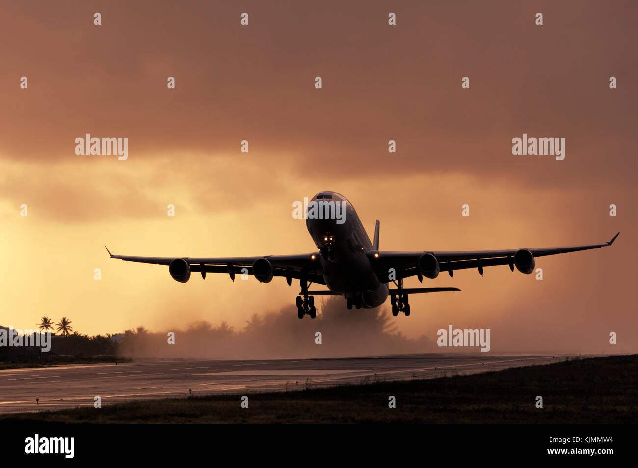 Airbus A340-313X take-off at dusk from a rainy wet runway with the engine exhaust making water spray Stock Photo