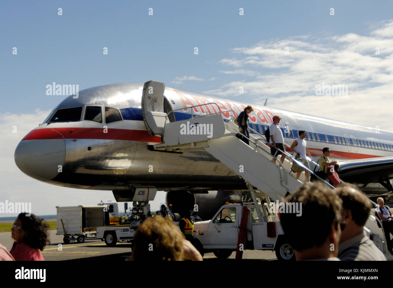 Passengers with carry-on bags disembarking using Menzies Ground Services airstairs from a American Airlines Boeing 757-200 parked Stock Photo