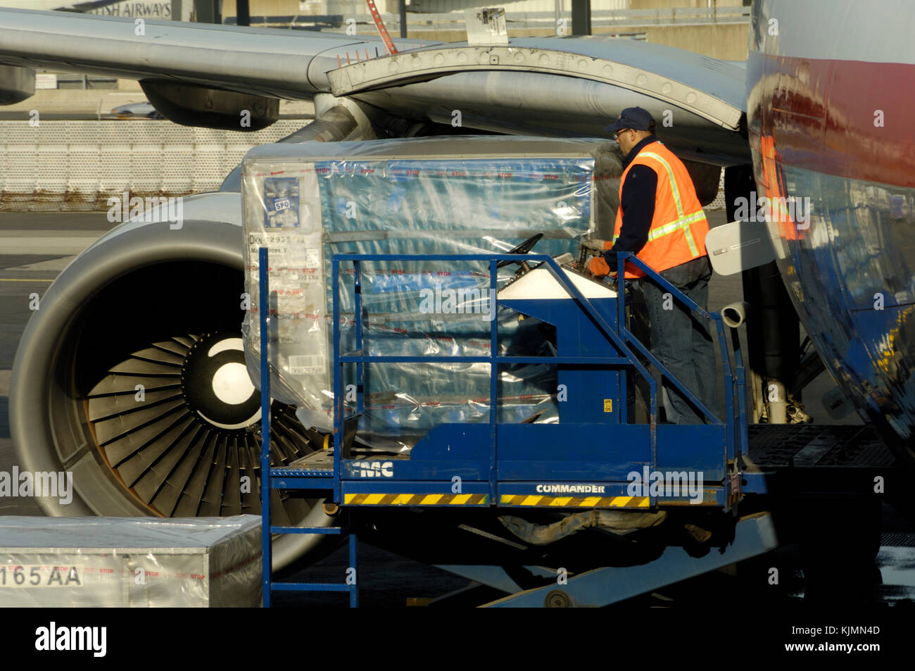 Man wearing an orange high-viz tabard unloading LD3 containers from an American Airlines Airbus A330-600R Stock Photo