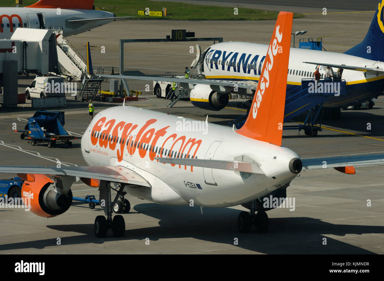 an easyJet Airbus A319-100 being pushed back with a Ryanair Boeing 737-800 and A319-100 parked at the South Terminal Stock Photo
