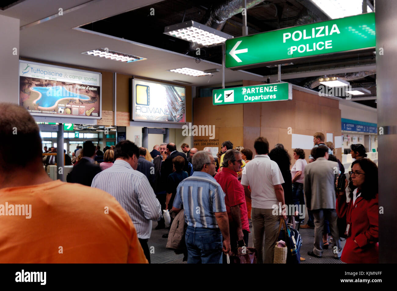 passengers with baggage queueing in the terminal with police and