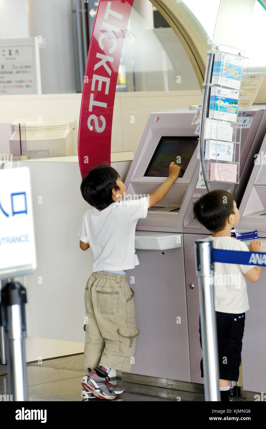 children passenger using e-ticket, e-check-in machine in main airport terminal building Stock Photo