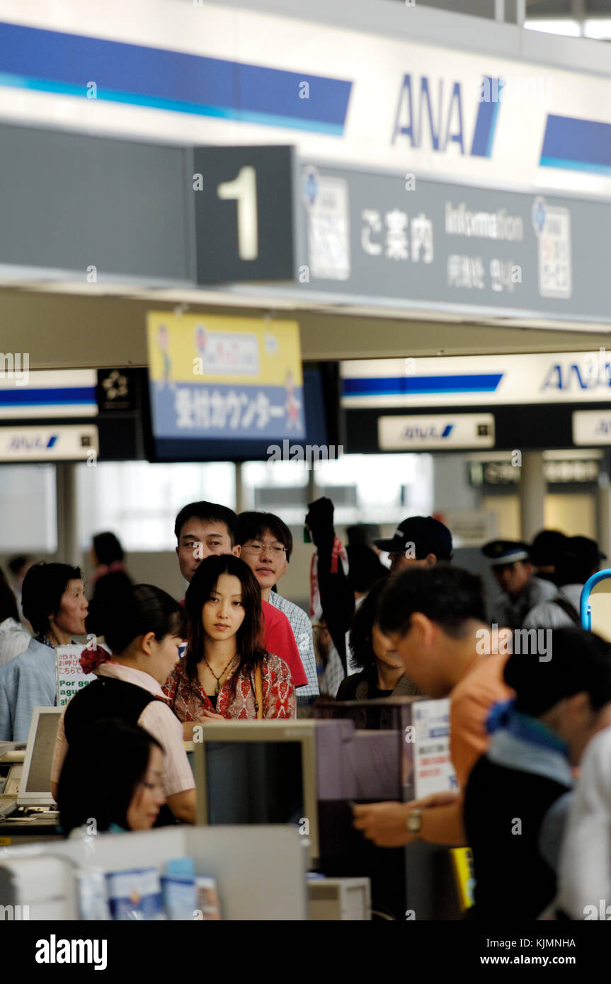 passengers queue at check-in desks in main airport terminal building Stock Photo