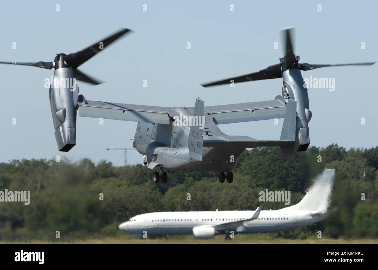 propellers and Rolls-Royce Allison T406 (AE-1107C-Liberty) engine cowlings of the US Marines Bell Boeing MV-22B Osprey taking-off with a Boeing Busine Stock Photo