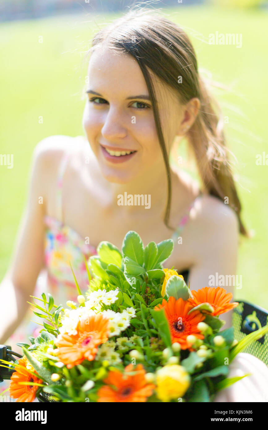 Portrait of a cute young woman with a bouquet of flowers in a summer ...