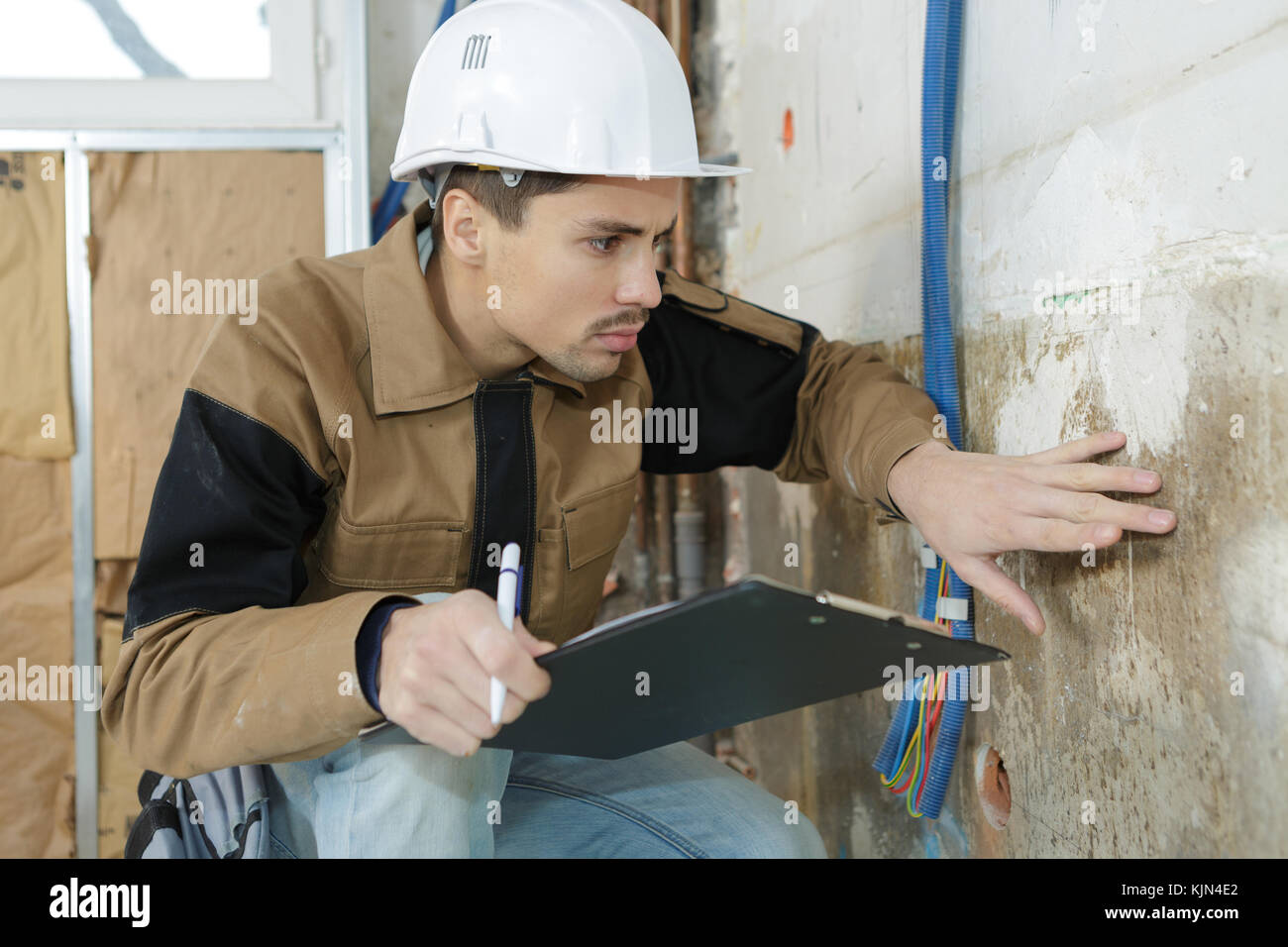 young male architect inspecting wall at construction site Stock Photo ...