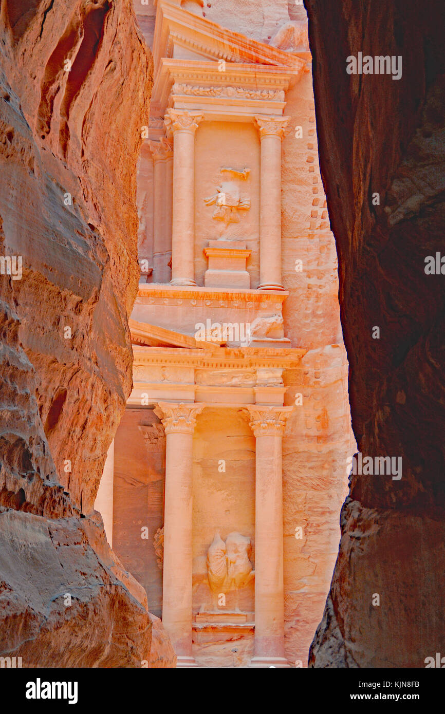 View of the Petra Treasury from a Siq (narrow gorge) leading into the main site. It is the most direct way into the site from the city of Petra. Stock Photo