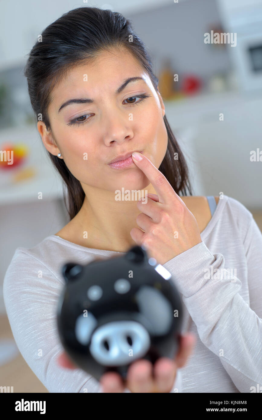 Curious woman holding a piggy bank Stock Photo - Alamy