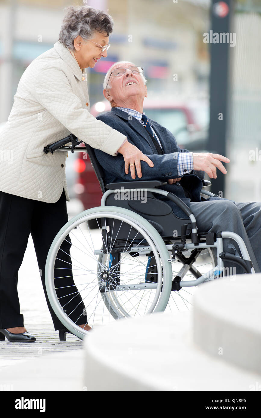 Senior Man In Wheelchair Being Pushed By Wife Stock Photo - Alamy