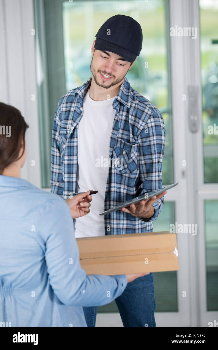 smiling young delivery man holding a cardboard box Stock Photo - Alamy