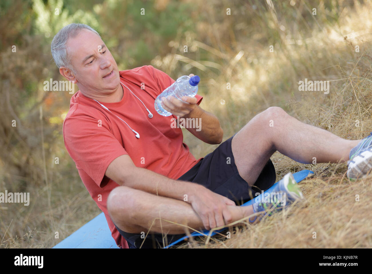 senior man sitting in park and holding bottle of water Stock Photo - Alamy