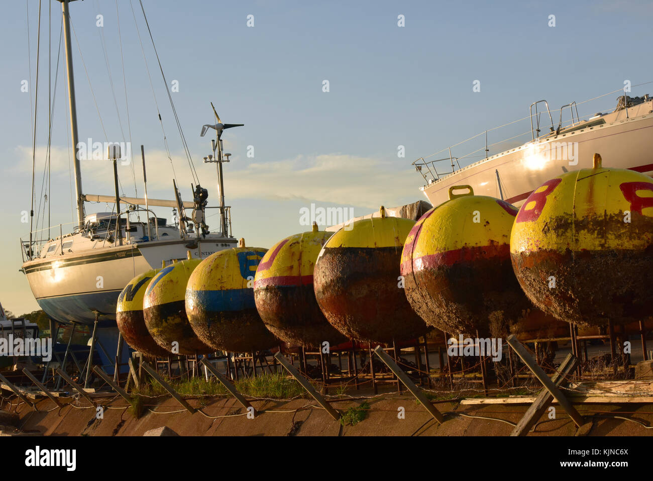 A row or line of navigation buoys in a boatyard at bembridge on the Isle of Wight. Trinity house navigation and buoy laying next to yachts on hard. Stock Photo