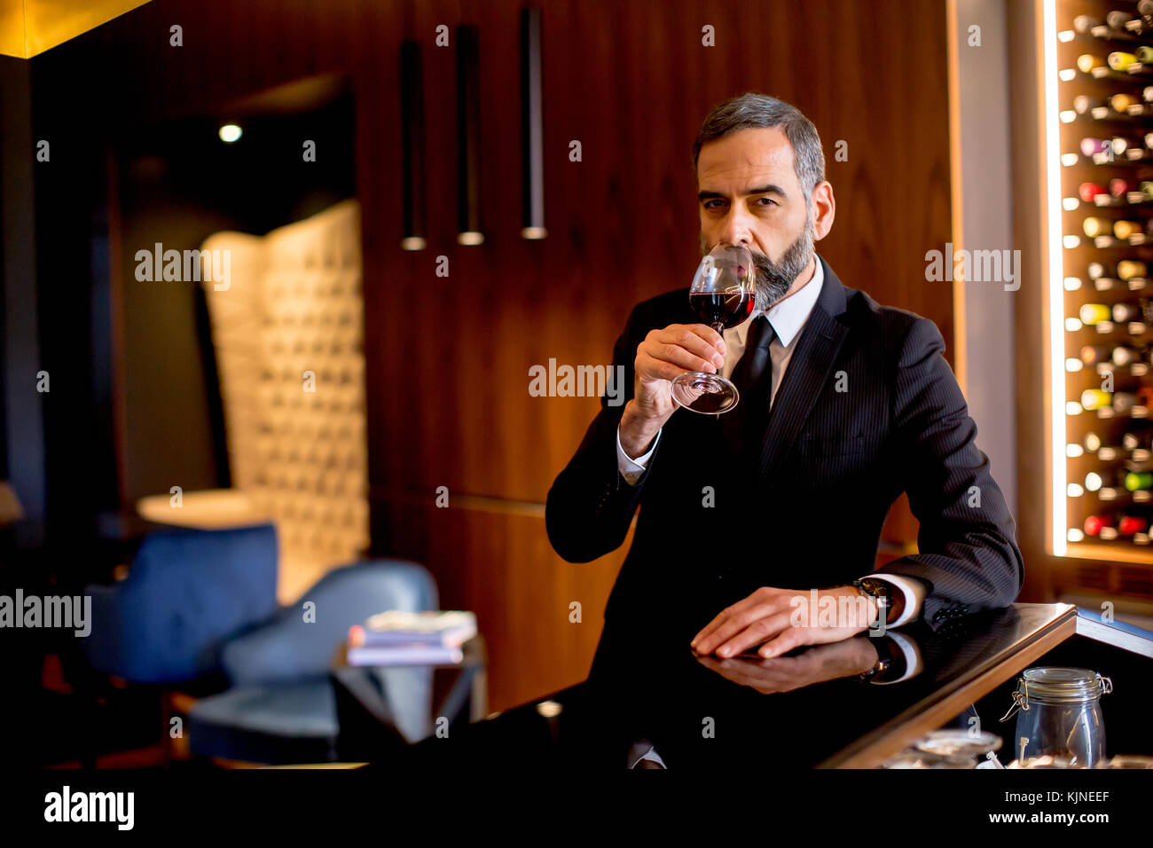 Handsome elegant businessman drinking red wine in bar Stock Photo - Alamy