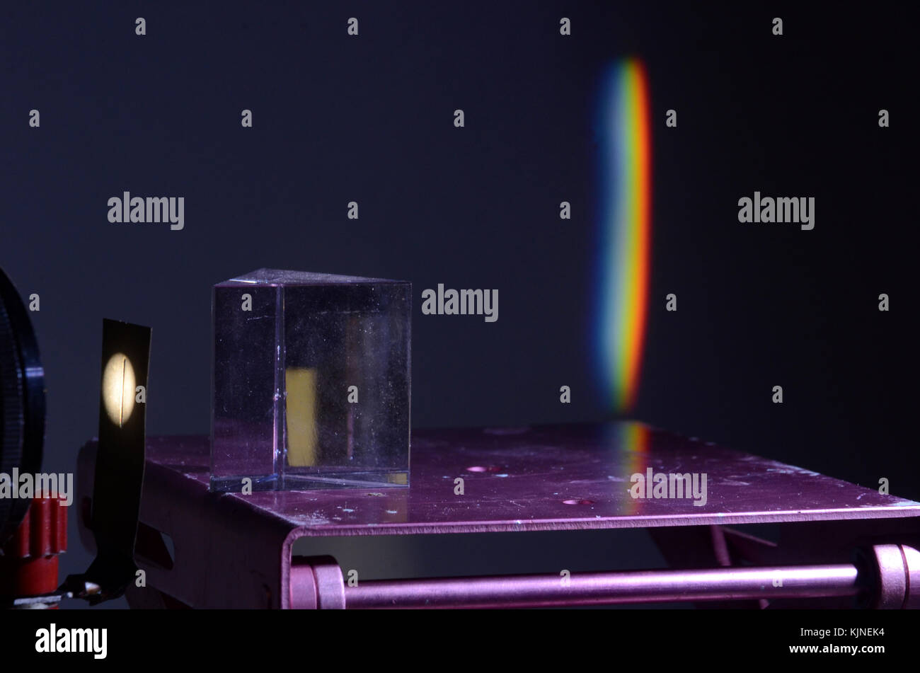Refraction of white light in a prism, a spectre is projected on the wall in the background. Stock Photo