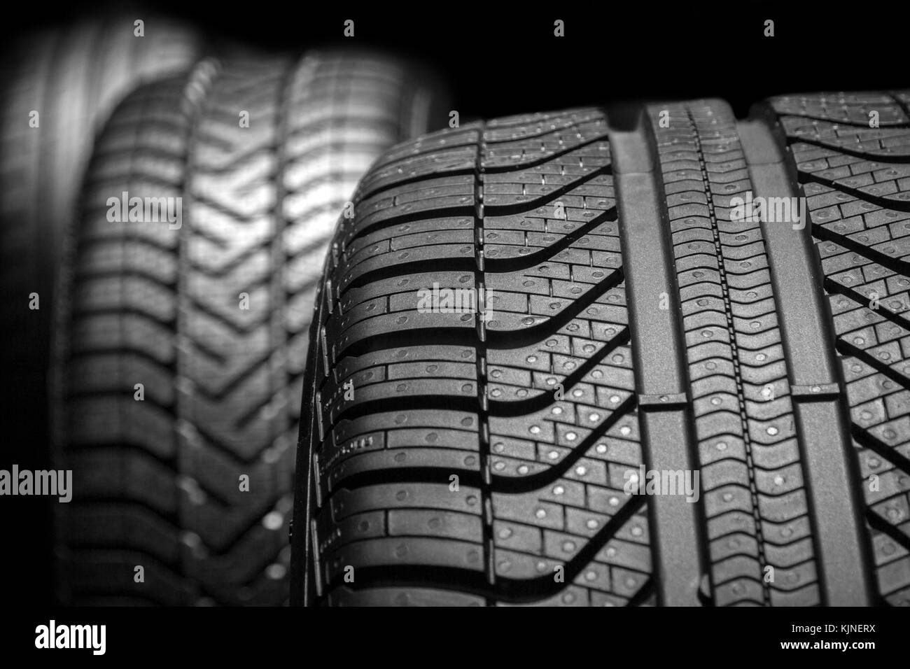 Row of car tires with a profile close-up on a black background. Stock Photo
