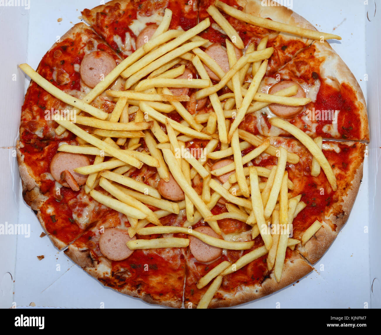 tasty pizza with fries and wurstel in the pizzeria of takeaway dishes Stock Photo