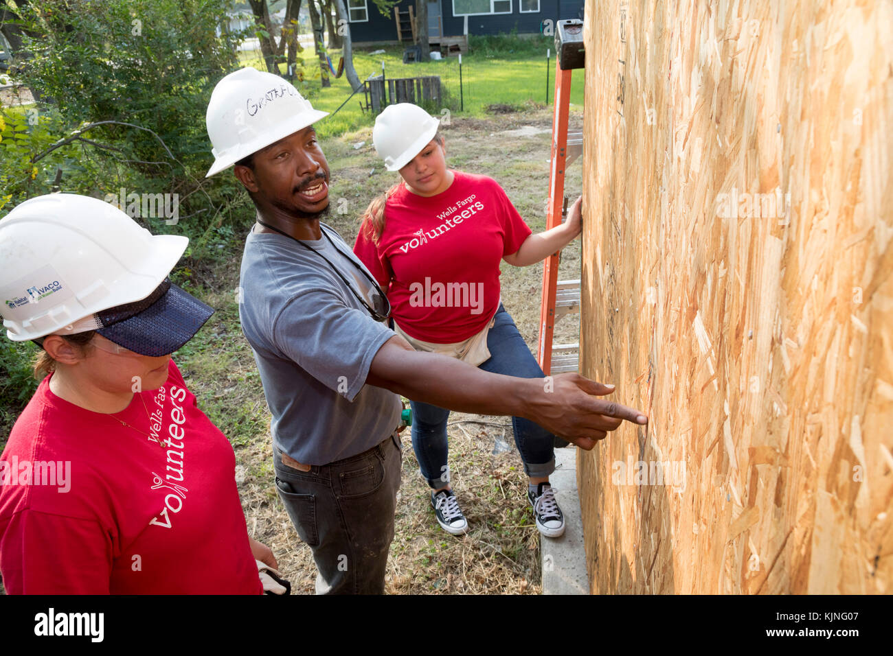 Houston, Texas - Two volunteers from Wells Fargo Bank get instruction as they help build a Habitat for Humanity house for a low-income family. The nee Stock Photo