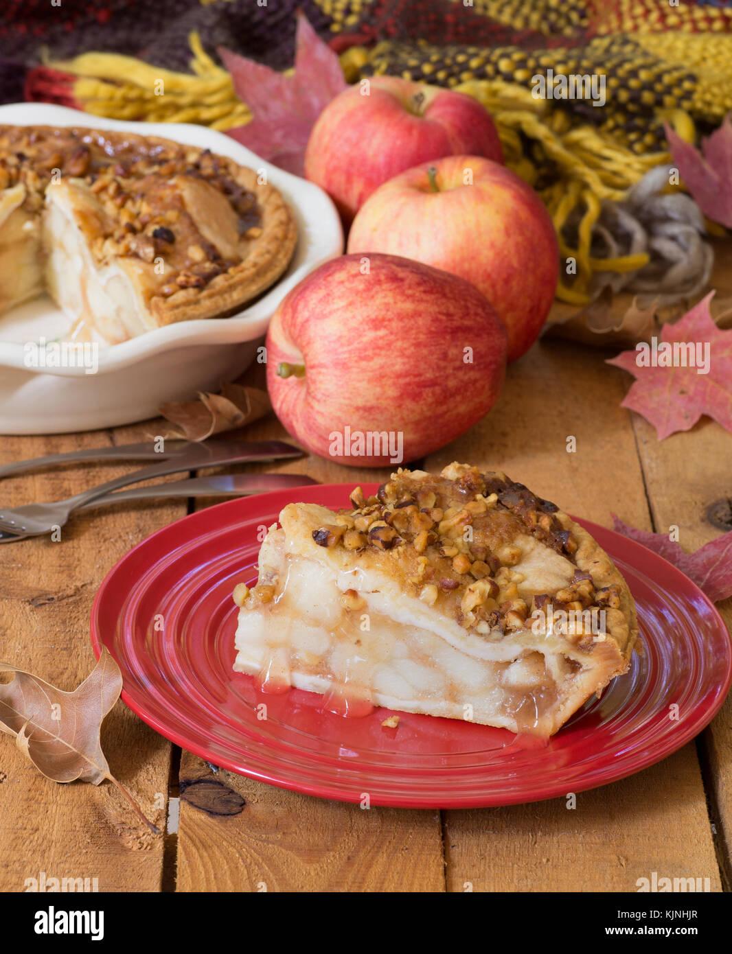 Slice of fresh apple pie with walnut topping on a wooden surface Stock Photo