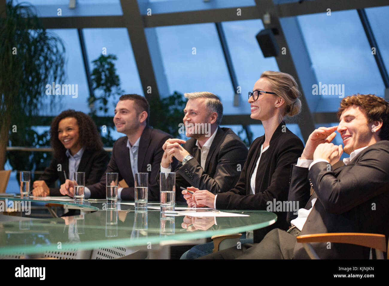 A group of business people sitting at a table discussing and laughing ...