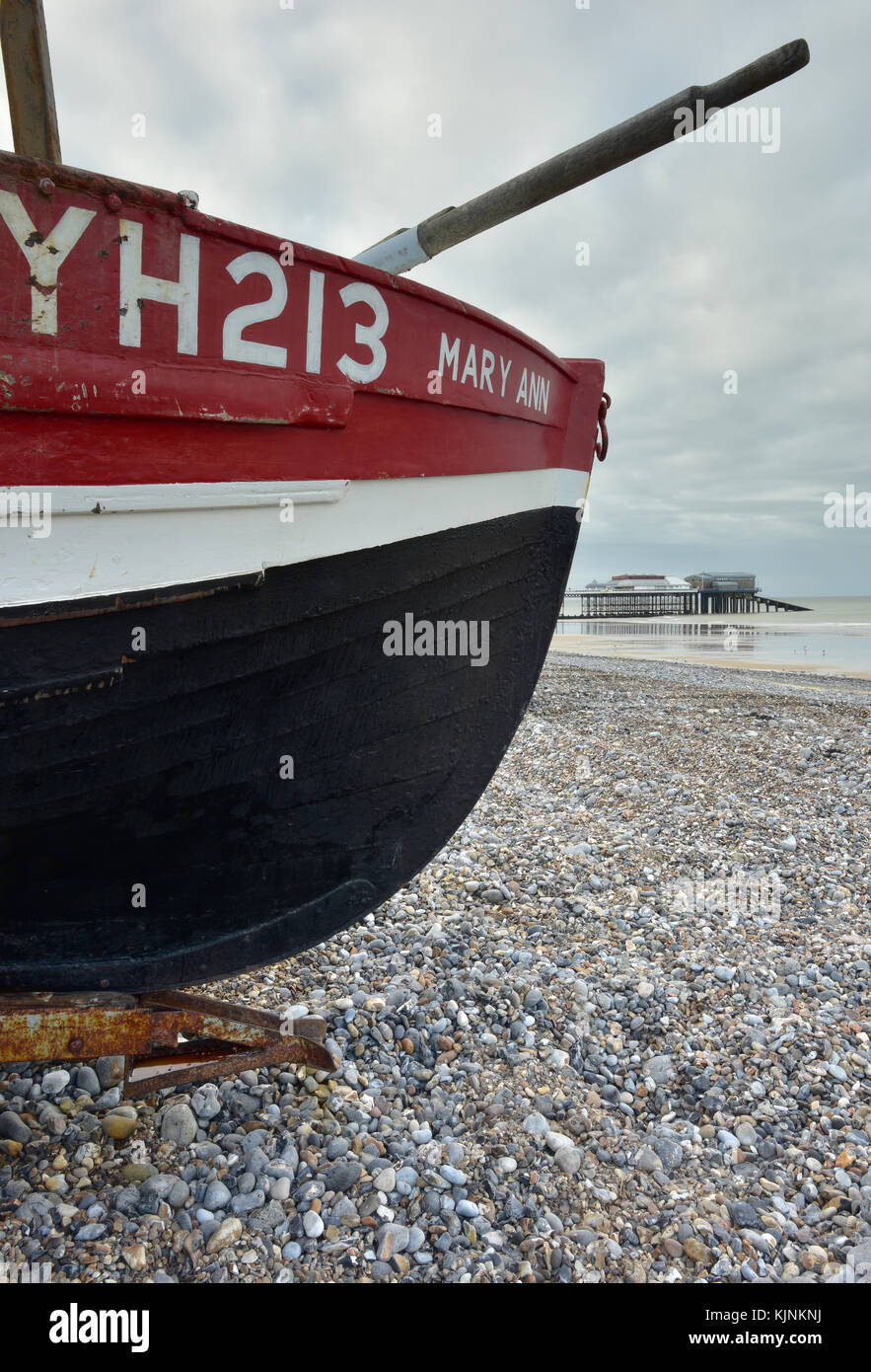 a traditional crab fishing boat on the beach at Cromer in Norfolk with oars sticking out from