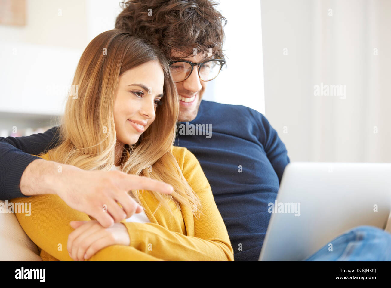 Shot of a lovely young couple relaxing on the couch and using a laptop ...