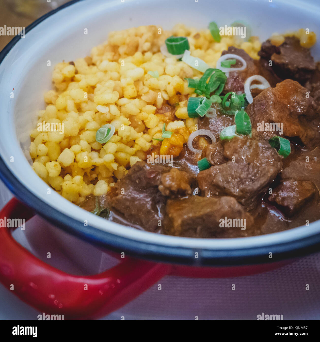Typical Hungarian beef Goulash served in an enamel plate with onion and spetzles. Square format. Stock Photo