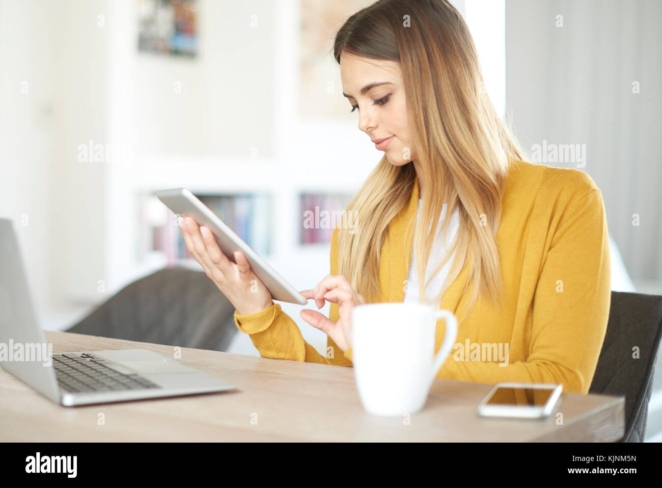 Shot of a young female student using her digital tablet and computer ...