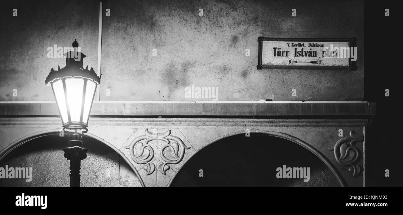 Black and white photo of a street lamp post and a vintage street name sign in Budapest (Hungary). June 2017. Landscape format. Stock Photo