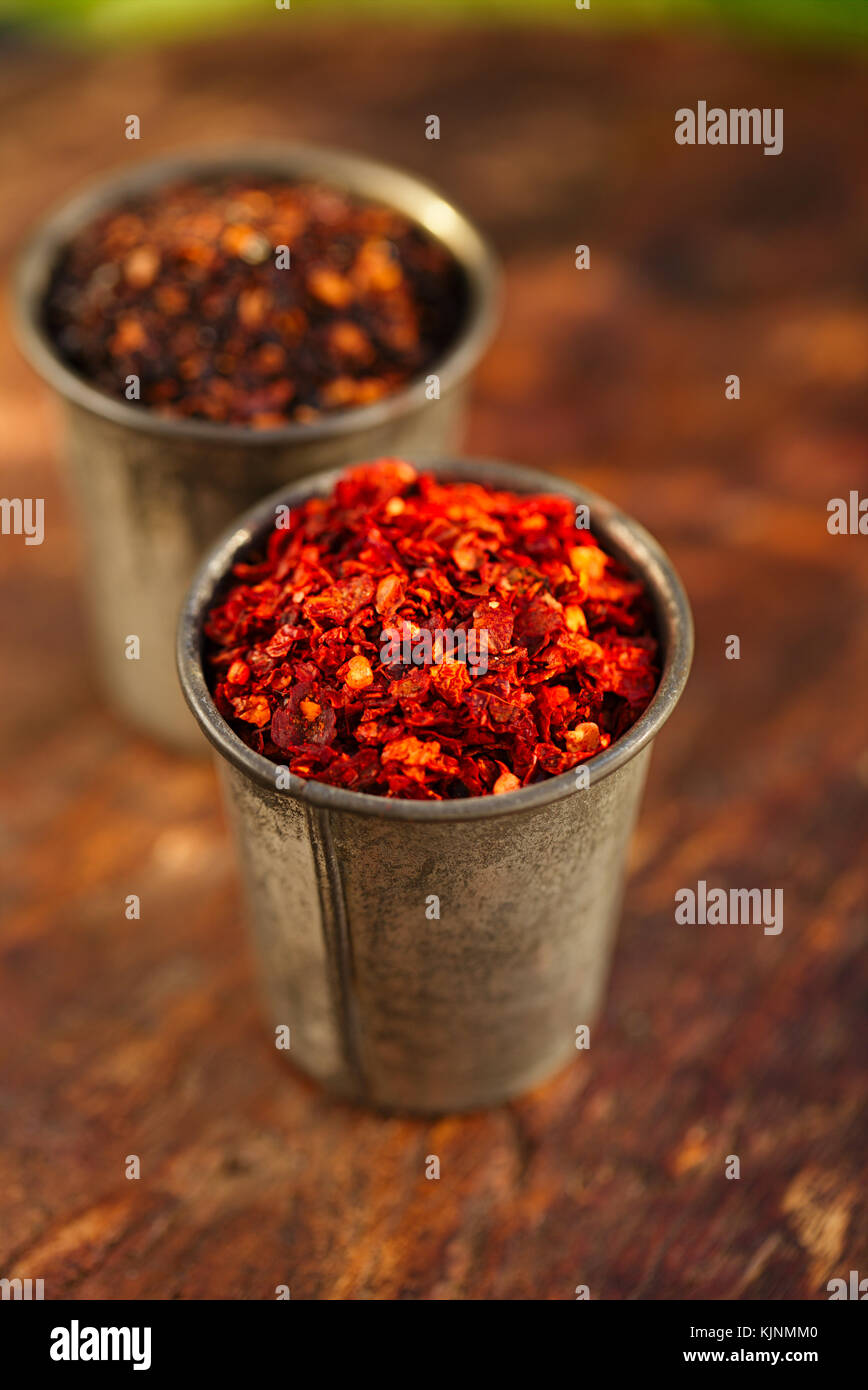 red hot chillies and chipotle jalapeno smoked chili flakes in vintage mould tin on textured woden background Stock Photo