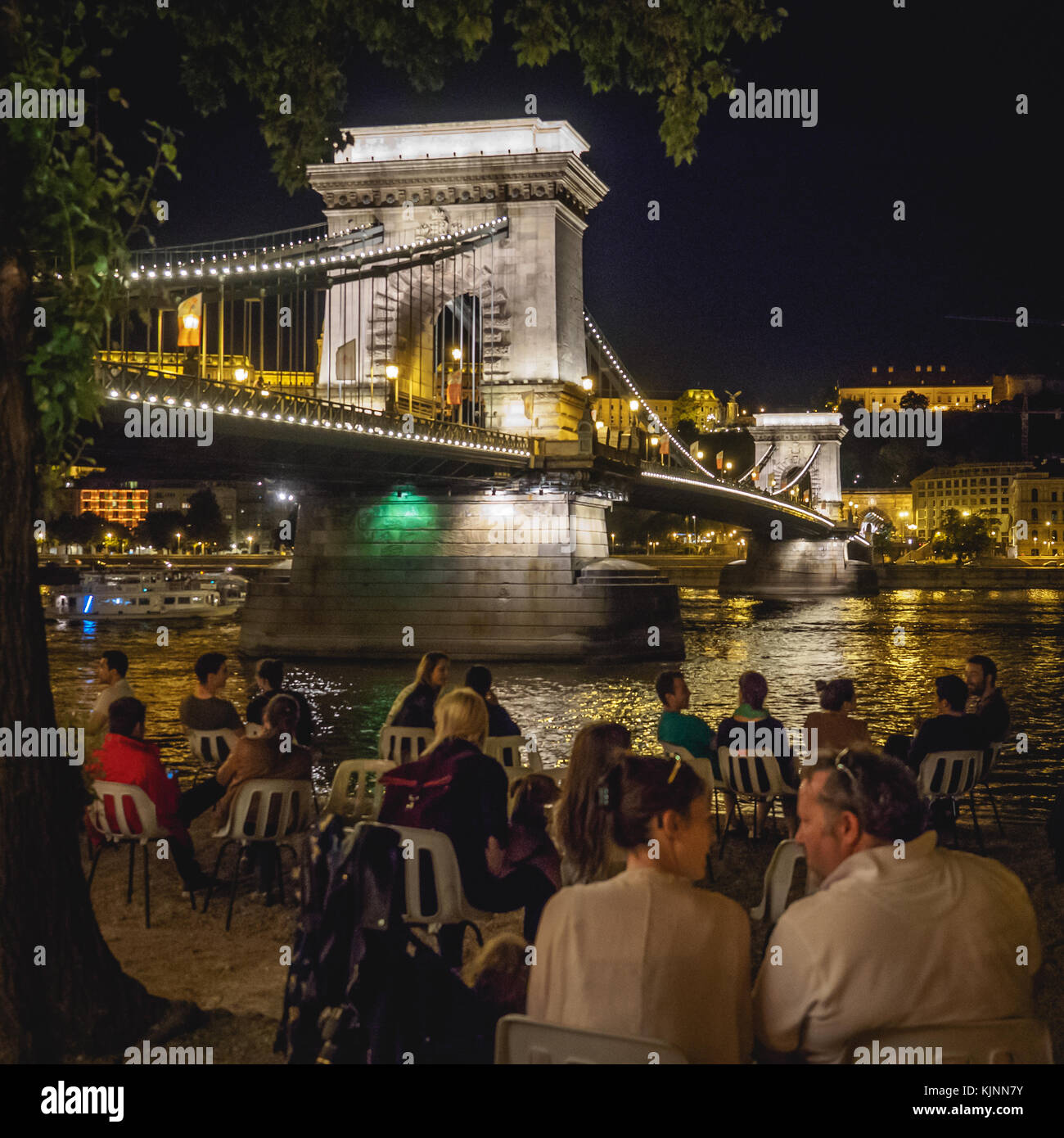 People in a bar on the Danube bank close to Széchenyi Lánchíd (Széchenyi Chain Bridge) in Budapest (Hungary). June 2017. Square format. Stock Photo