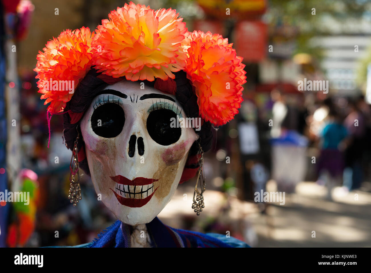 Skull painted and decorated with orange paper mache flowers and earrings/decorated skull for Dia de los Muertos, Day of the Dead Stock Photo